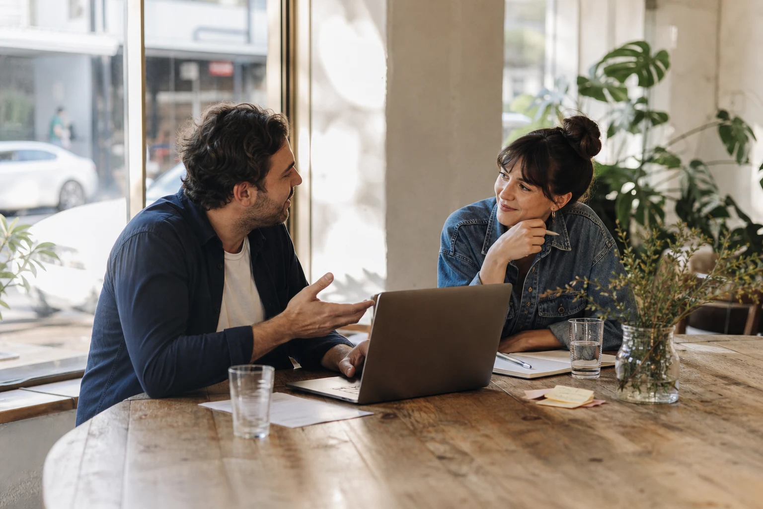 Two colleagues collaborating at a sunlit shared workspace.